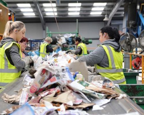 Workers in hi-vis sorting recycling on a conveyor