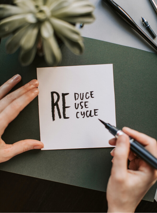 A note being written which reads: Reduce, reuse, recycle